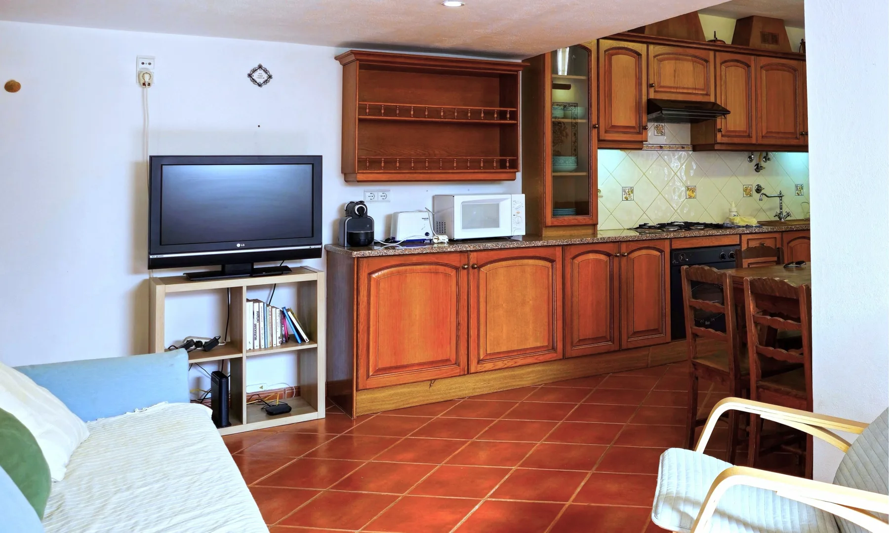 Una sala de estar con televisor y una cocina contigua con armarios de madera.