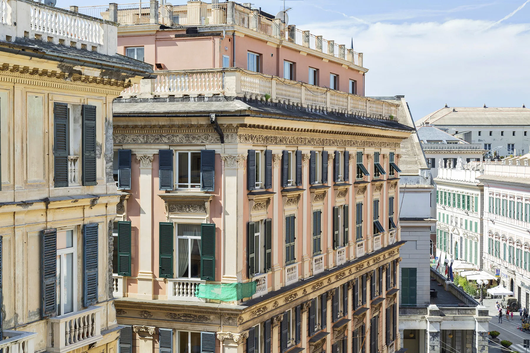 Una calle soleada bordeada de edificios históricos con ventanas con persianas.