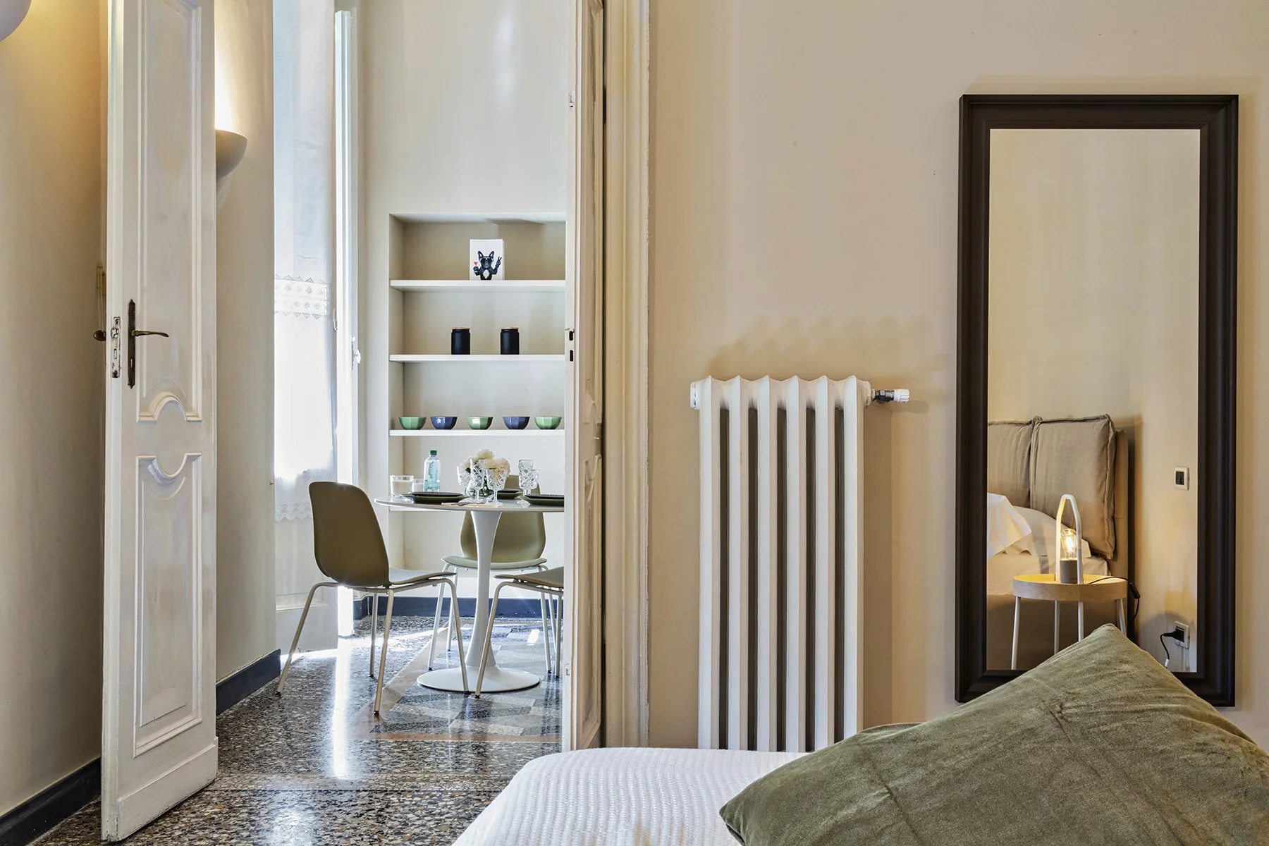 Un dormitorio con una cama en primer plano y un radiador junto a la puerta.