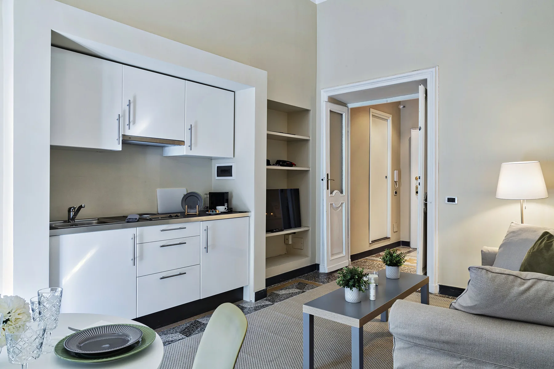 Una cocina compacta y sala de estar con gabinetes blancos y una zona para sentarse.