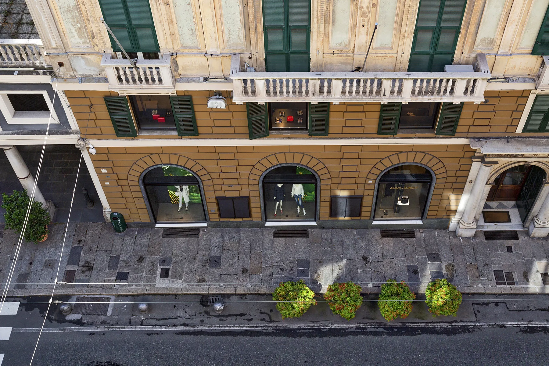 Una fachada de edificio con ventanas arqueadas en la planta baja da a una acera pavimentada.