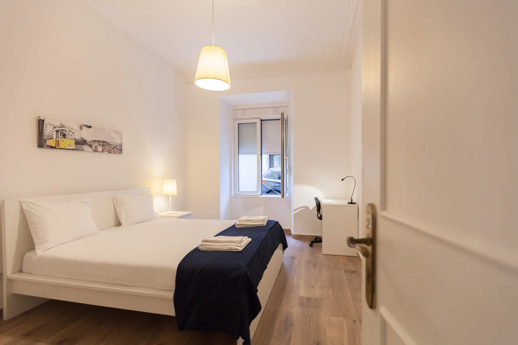 A bedroom with a bed, bedside lamp, and window.