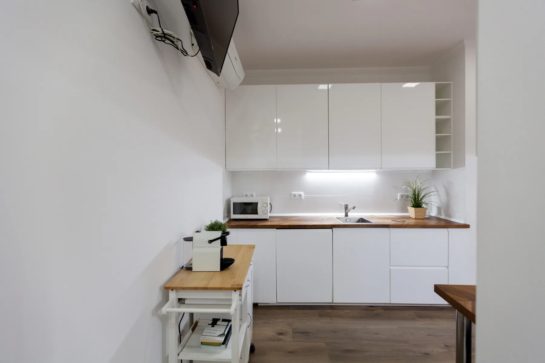 A bright kitchen with white cabinets, a countertop, and a small dining table.