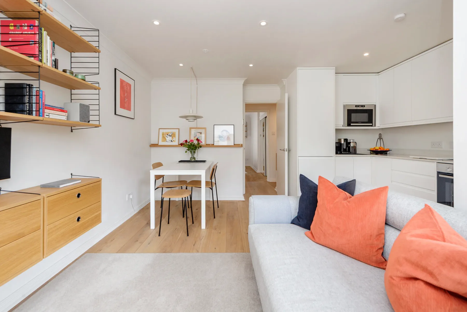 A bright open-plan living and dining area with a white kitchen.