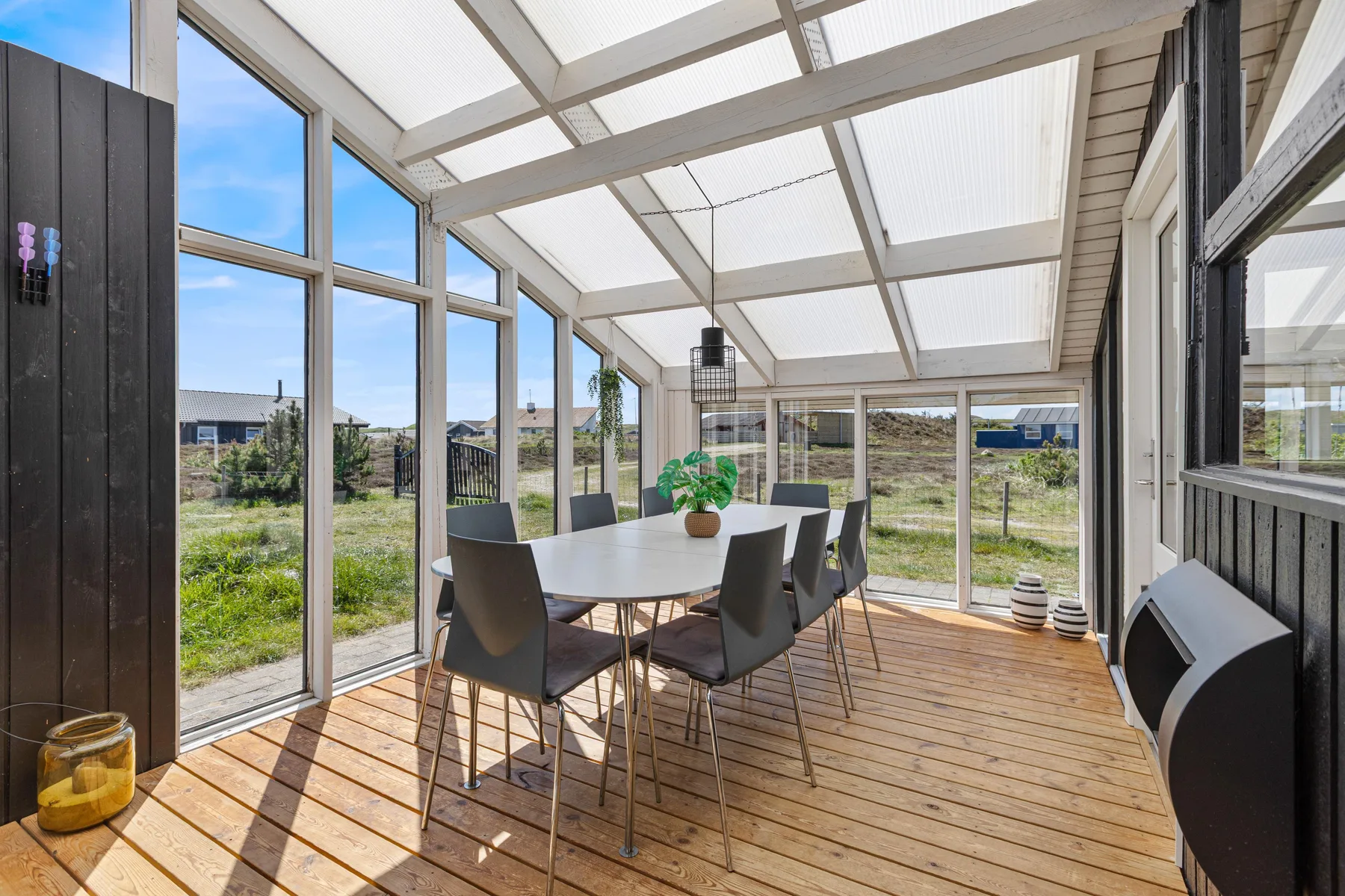 A sunroom dining area with a table and chairs beside large windows.