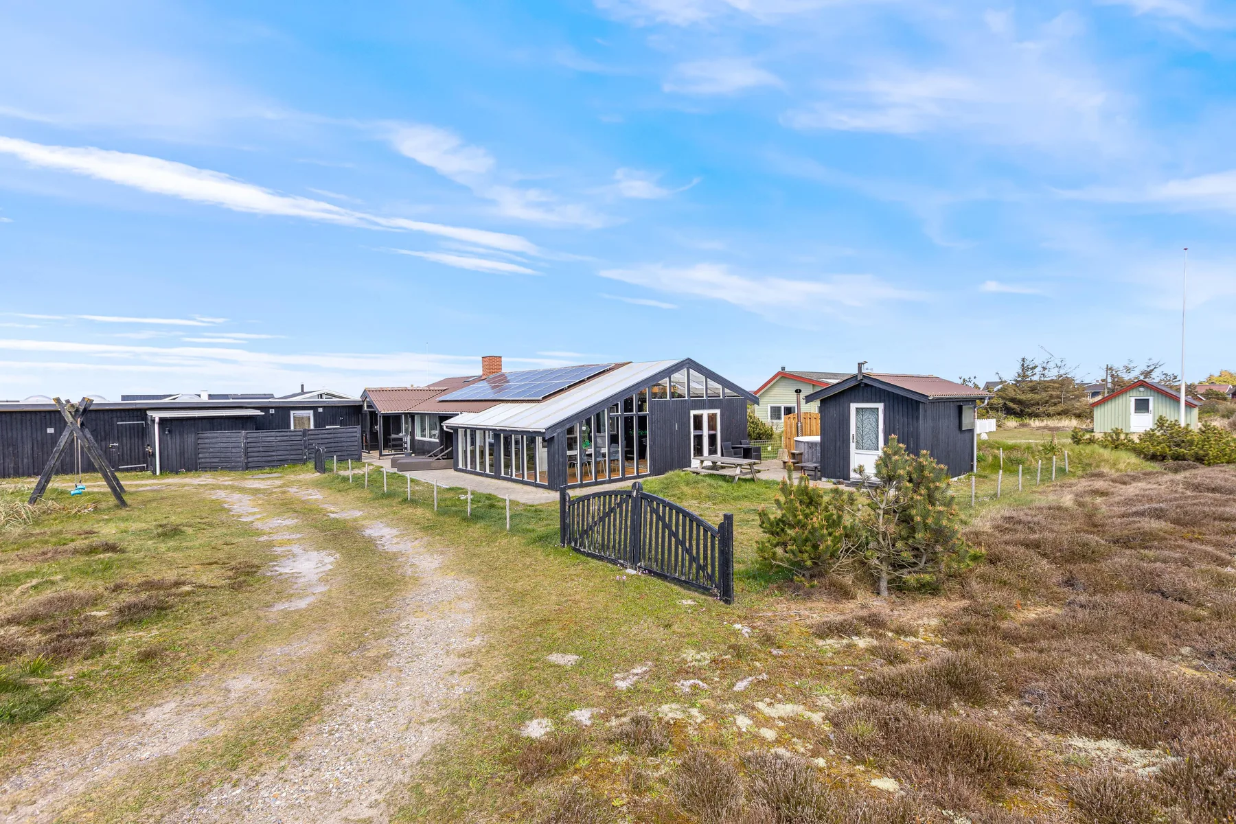 A holiday home and surrounding cottages sit beside a grassy path.