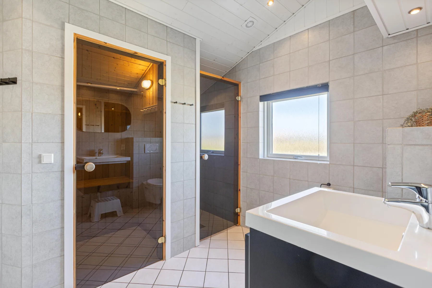 A tiled bathroom with a bathtub, sink, and a separate shower area.