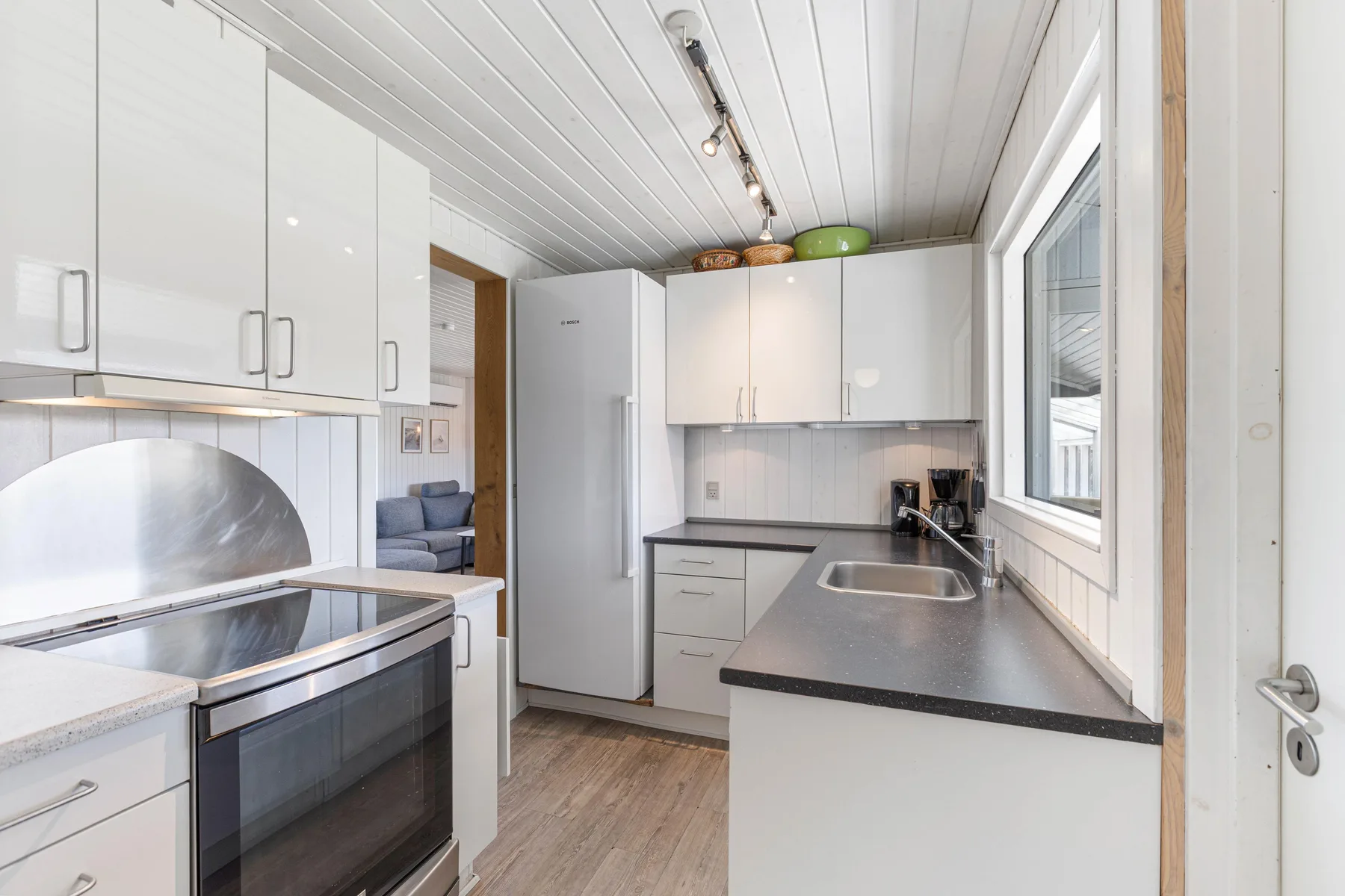 A bright kitchen with white cabinets, a refrigerator, and a countertop.
