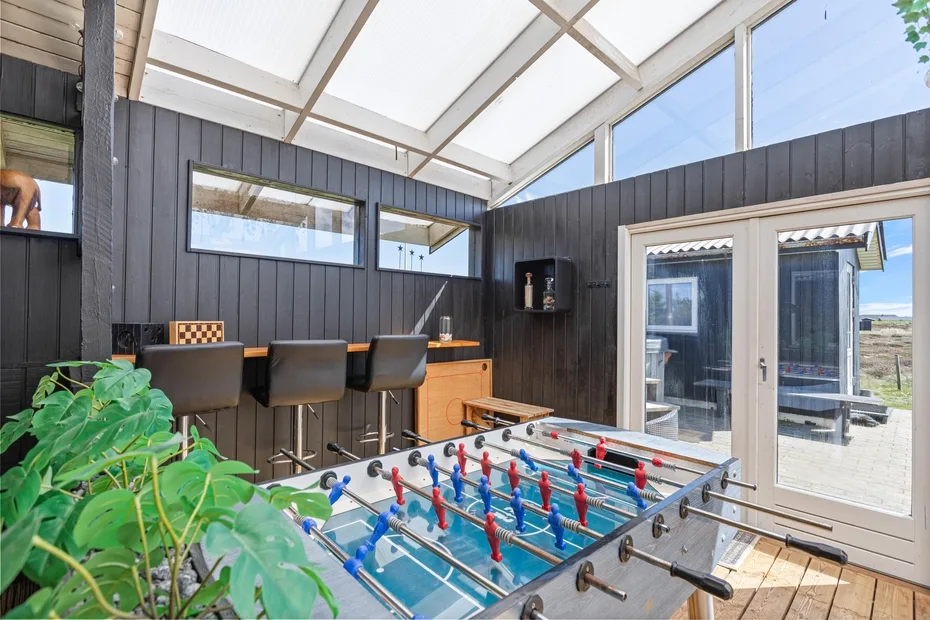 A bright game room features a foosball table beside a bar counter.
