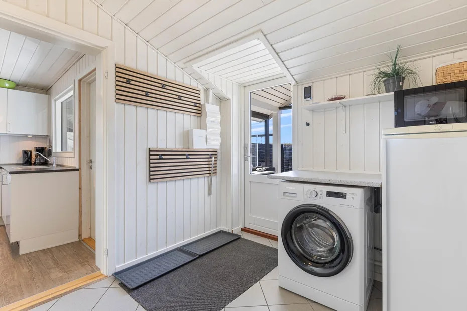 Laundry room with a washing machine and a small adjoining kitchen.