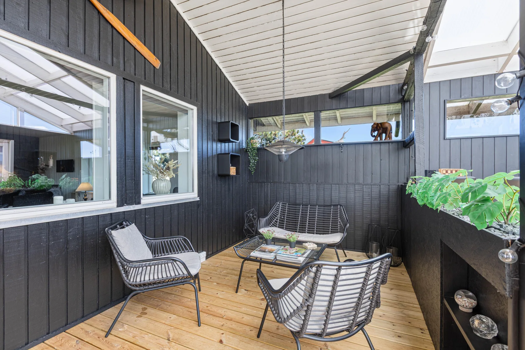 A covered outdoor seating area with a wooden deck and dark walls.