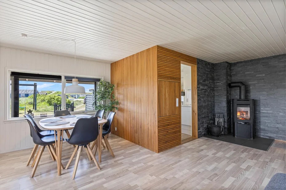 An open dining and living area with a wooden dining table and a black stove.