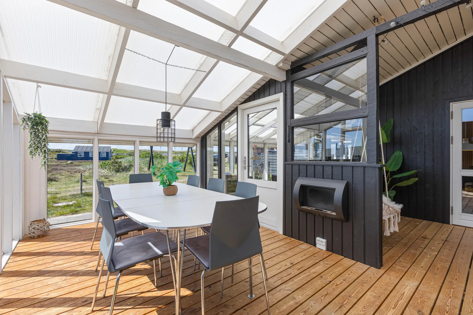 A bright dining area under a glass roof, with a table beside large windows.