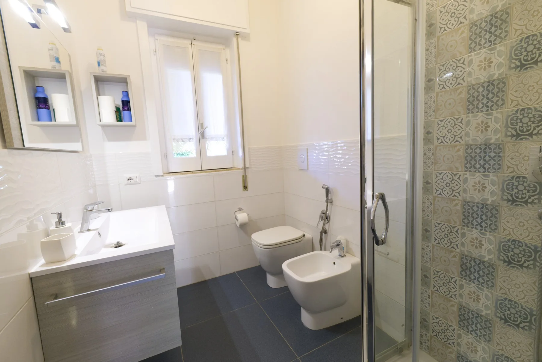 A bathroom with a vanity, toilet, bidet, and glass shower.