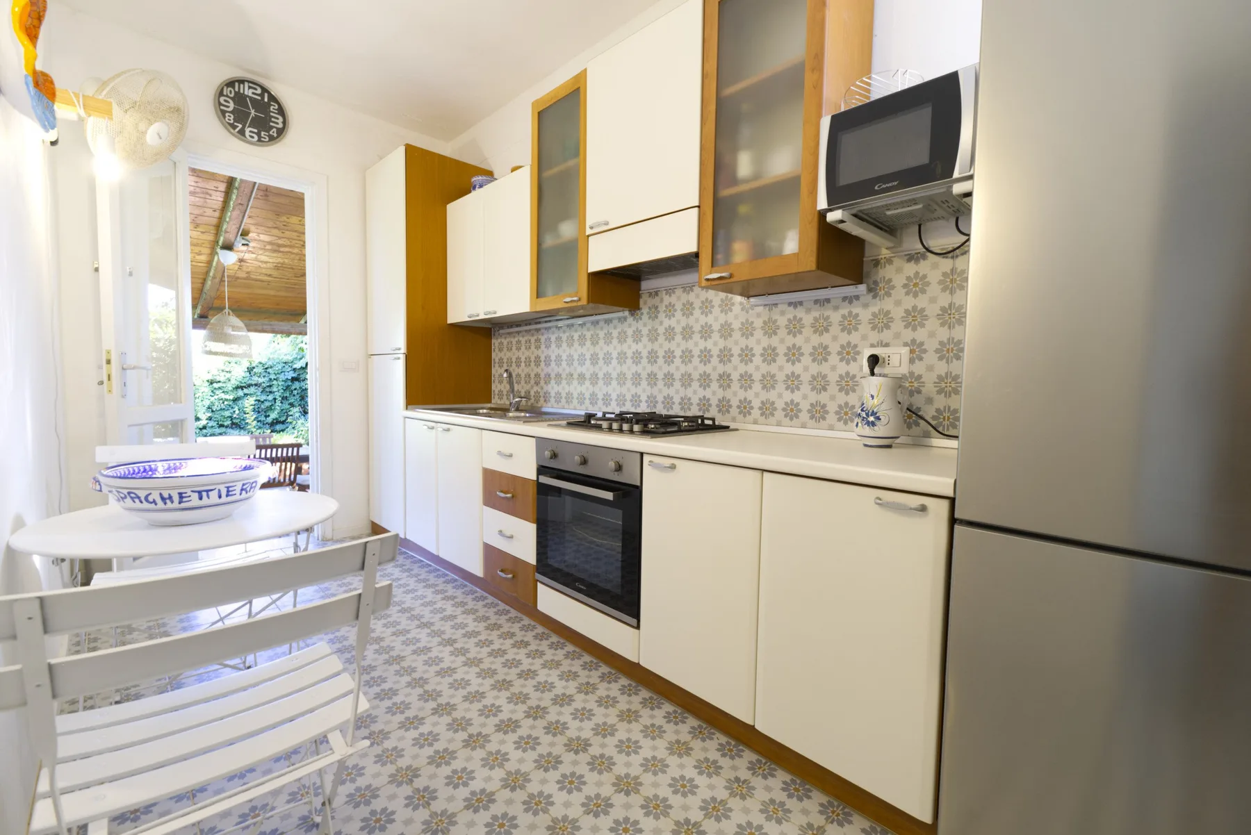 A narrow kitchen with fitted cabinets, a stove, and a small dining table.