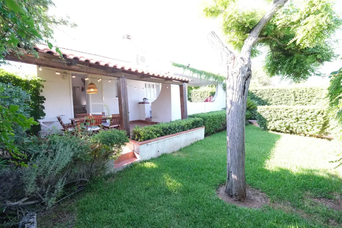 Un patio ajardinado con asientos al aire libre junto a un césped frondoso.