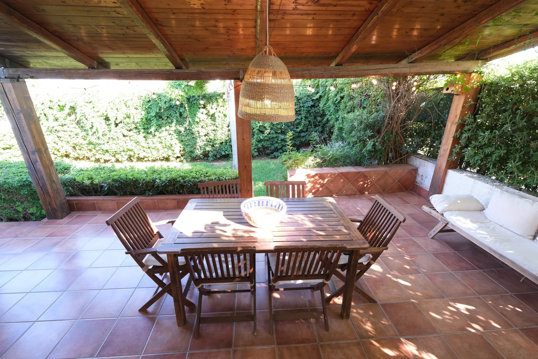 Comedor exterior cubierto con una mesa de madera y asientos.