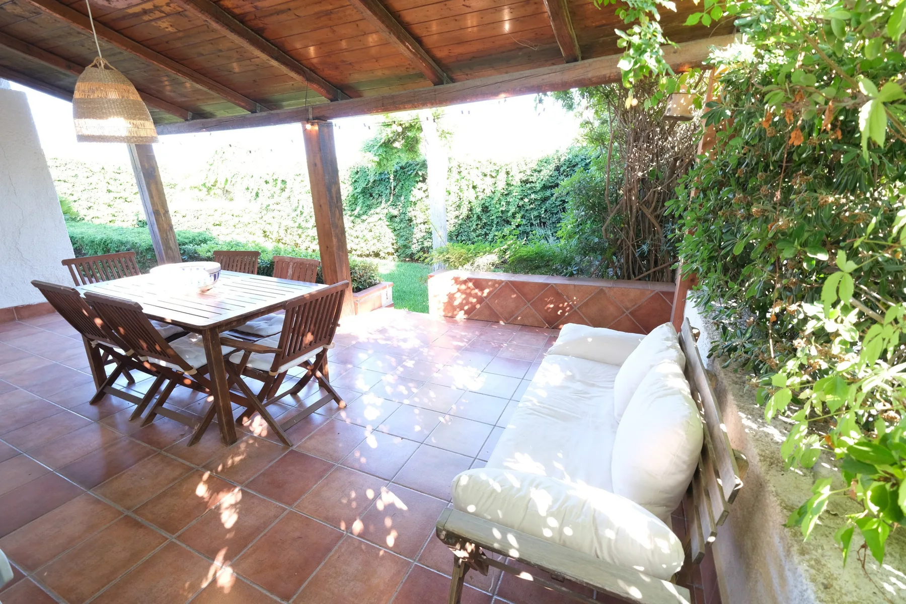 A covered outdoor patio with a dining table and cushioned seating.