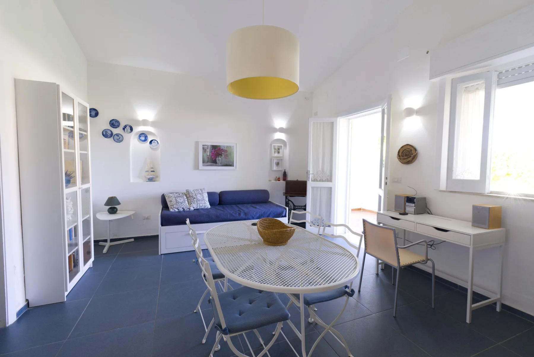 A bright living room with seating, a round dining table, and large windows.
