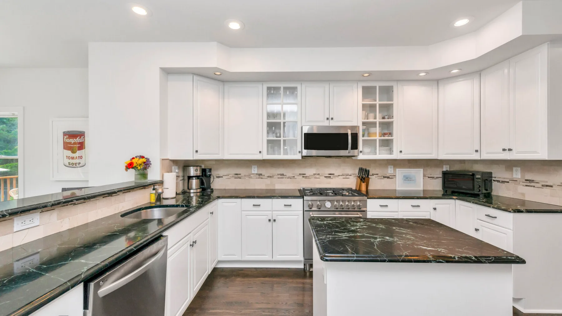 Una cocina luminosa con gabinetes blancos y una isla central.