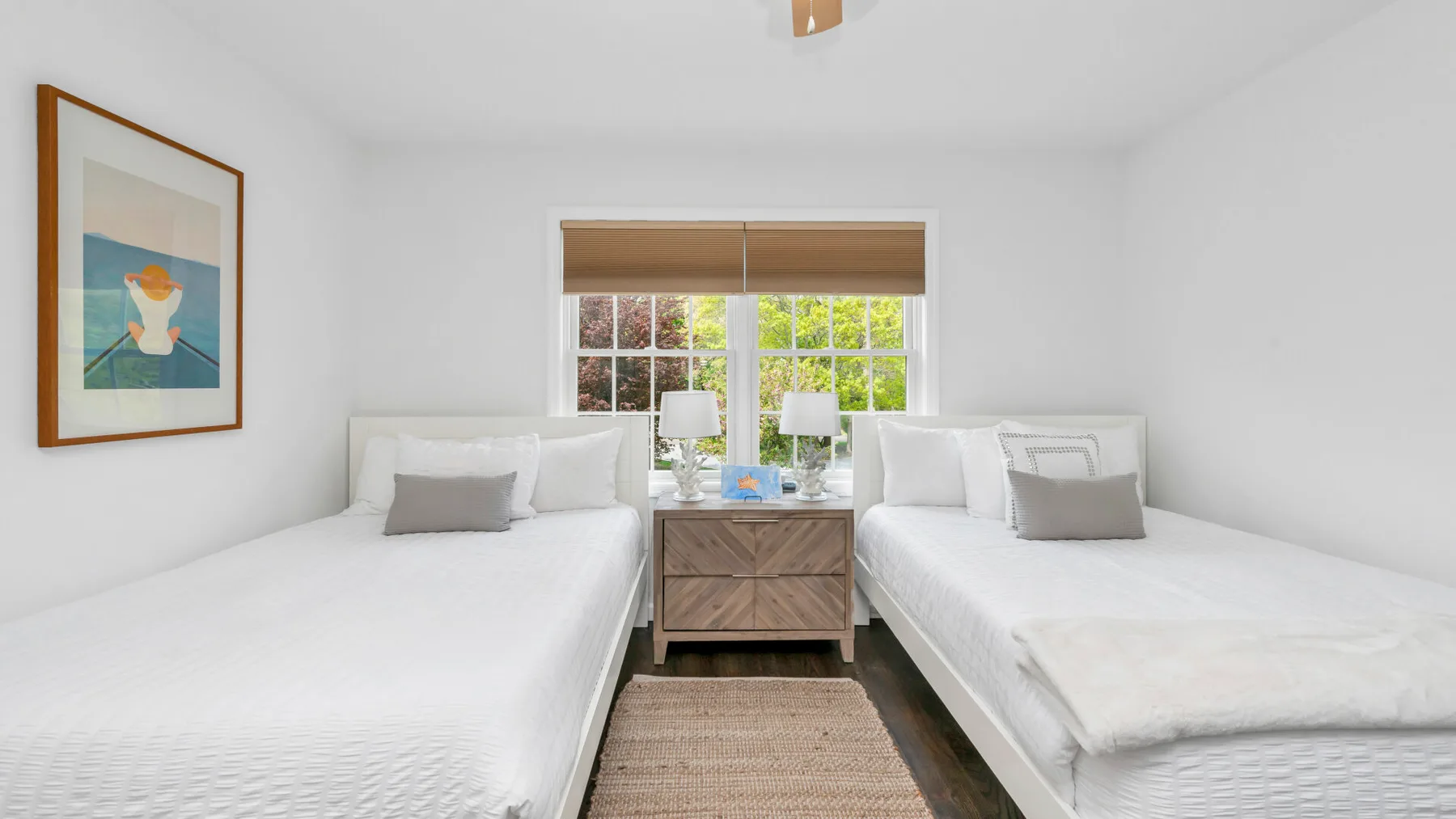 Un dormitorio luminoso con dos camas y una ventana que da a la vegetación.