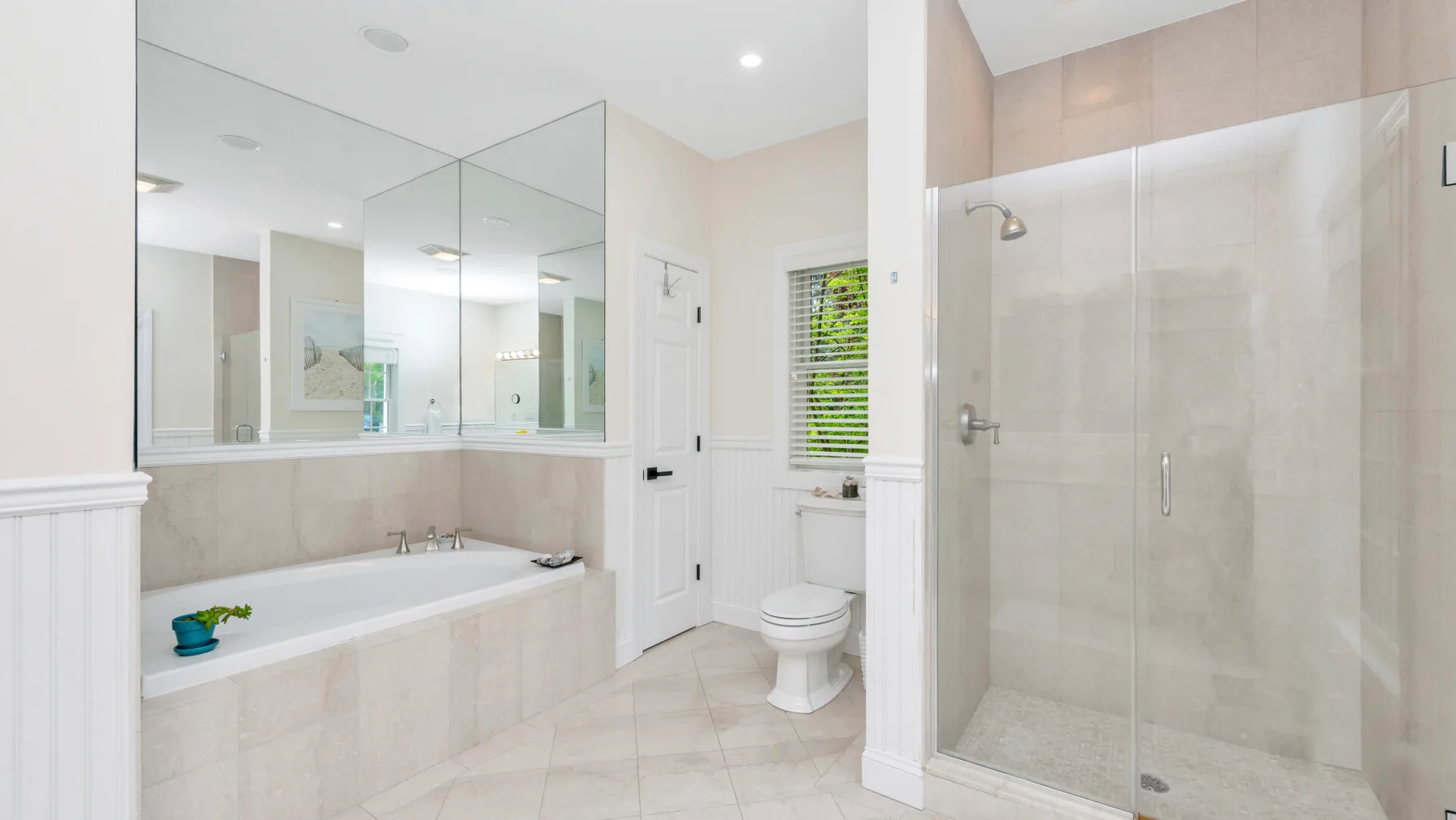 Un baño luminoso con bañera, ducha de vidrio e inodoro.