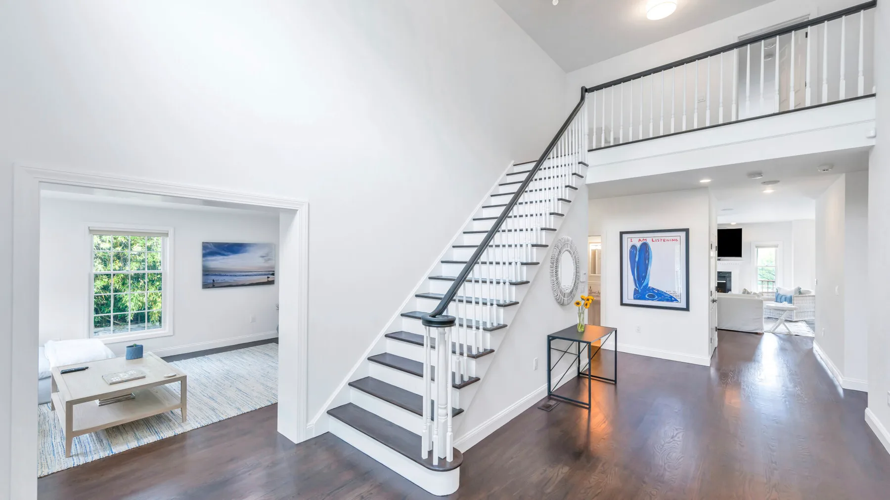 Un pasillo interior luminoso presenta una escalera y una sala de estar abierta.