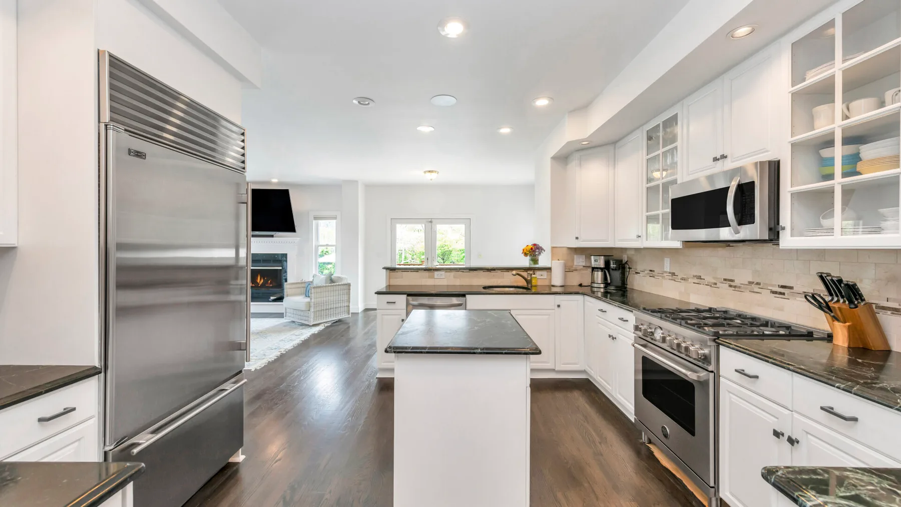 Una cocina luminosa con gabinetes blancos, electrodomésticos de acero inoxidable e isla central.