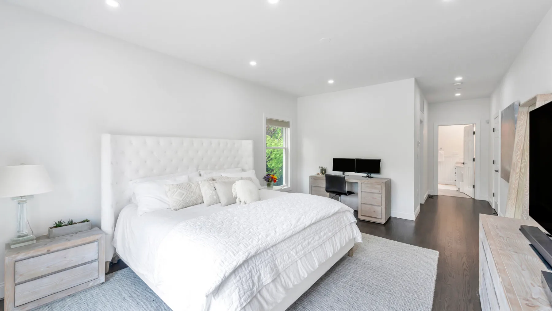 Un dormitorio luminoso con una cama grande, mesitas de noche y un televisor.