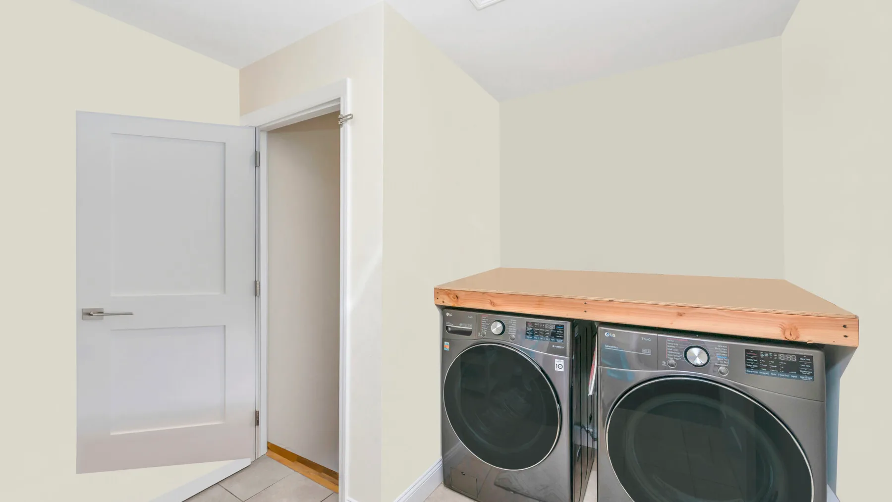 Una zona de lavandería con lavadora y secadora bajo una encimera de madera.
