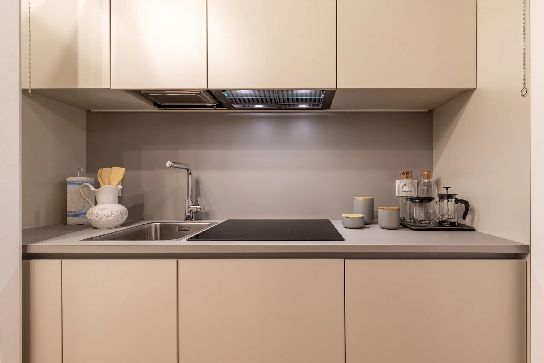 Una encimera de cocina moderna con fregadero, placa de cocina y armarios superiores.