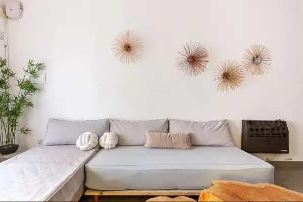 A bright living room has a light-colored sectional sofa and decorative wall pieces.
