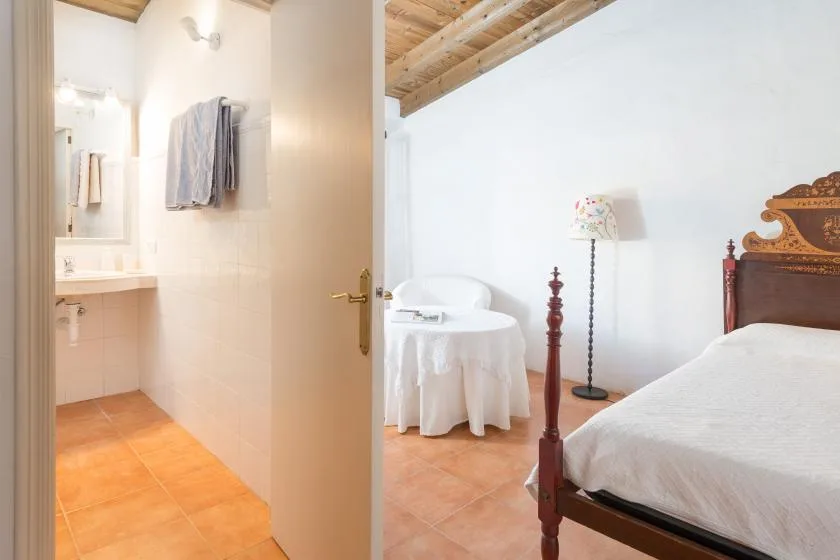 Un dormitorio con una cama, una mesa pequeña y un baño contiguo.