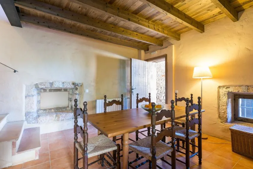 Un comedor rústico con una mesa de madera y sillas bajo vigas de techo expuestas.