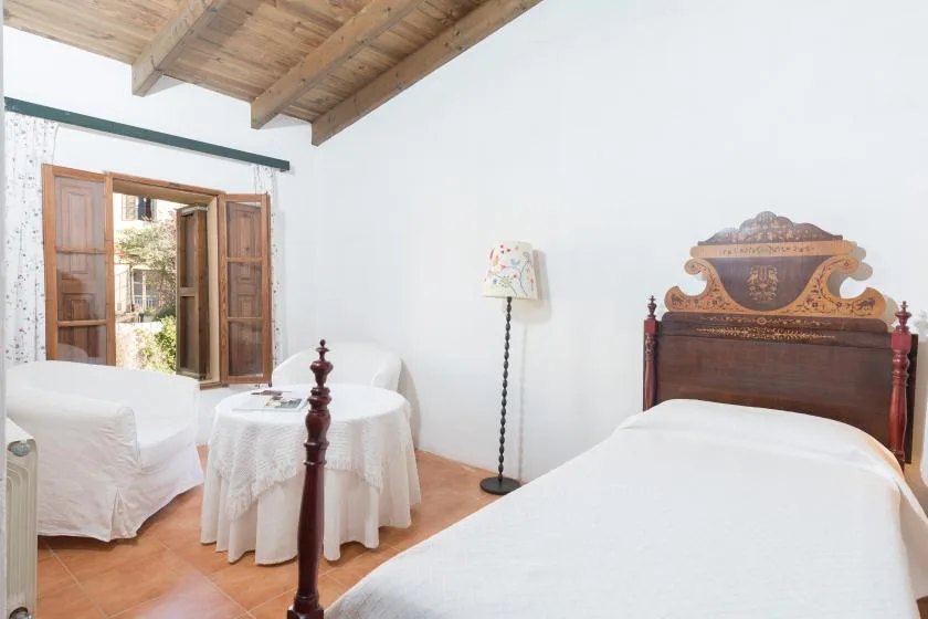 Un dormitorio con dos camas, una mesa pequeña y una ventana de madera abierta.