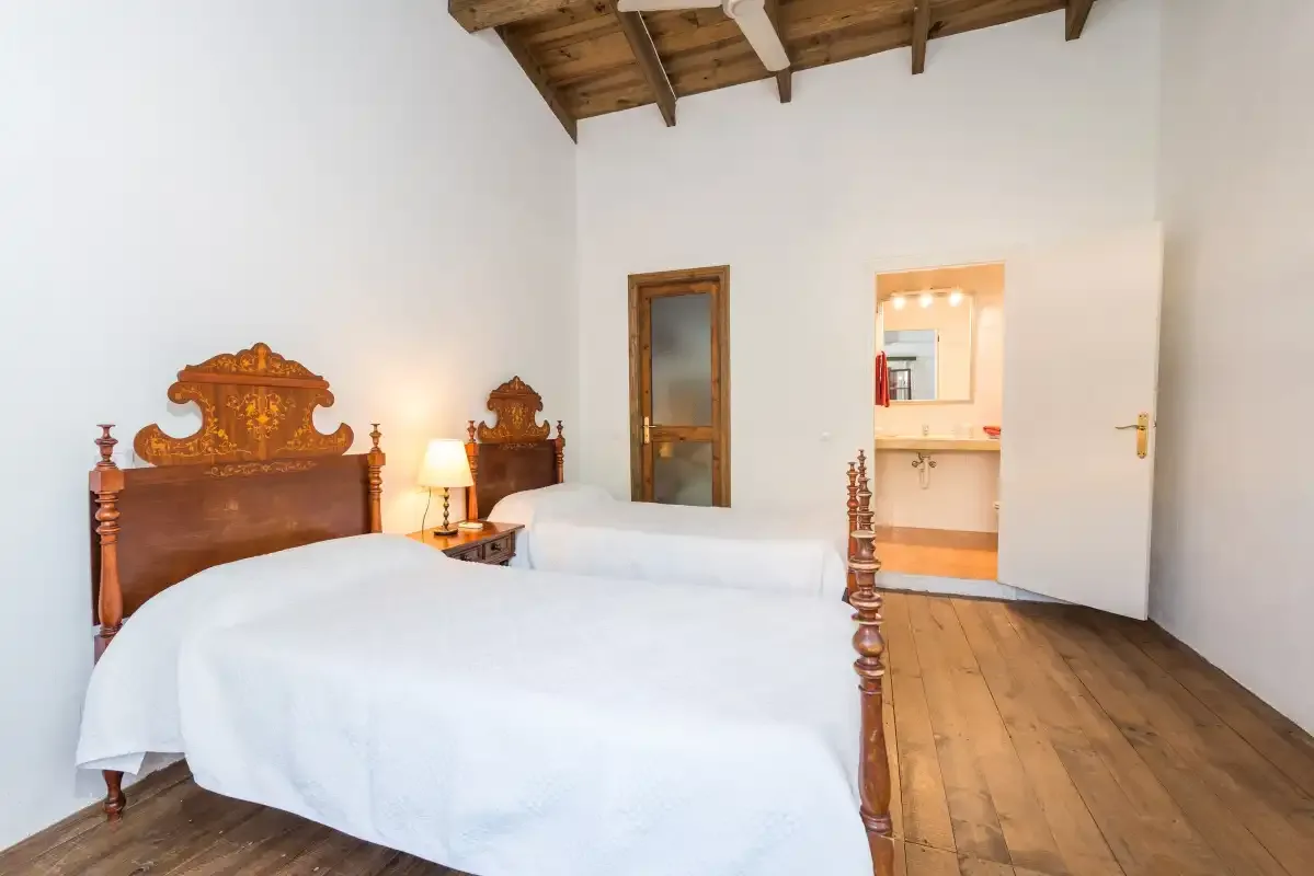 Un dormitorio con dos camas, cabeceros de madera y una puerta abierta.