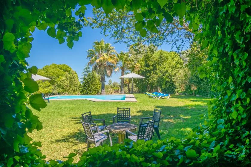 Un jardín frondoso rodea una zona de estar al aire libre junto a una piscina.