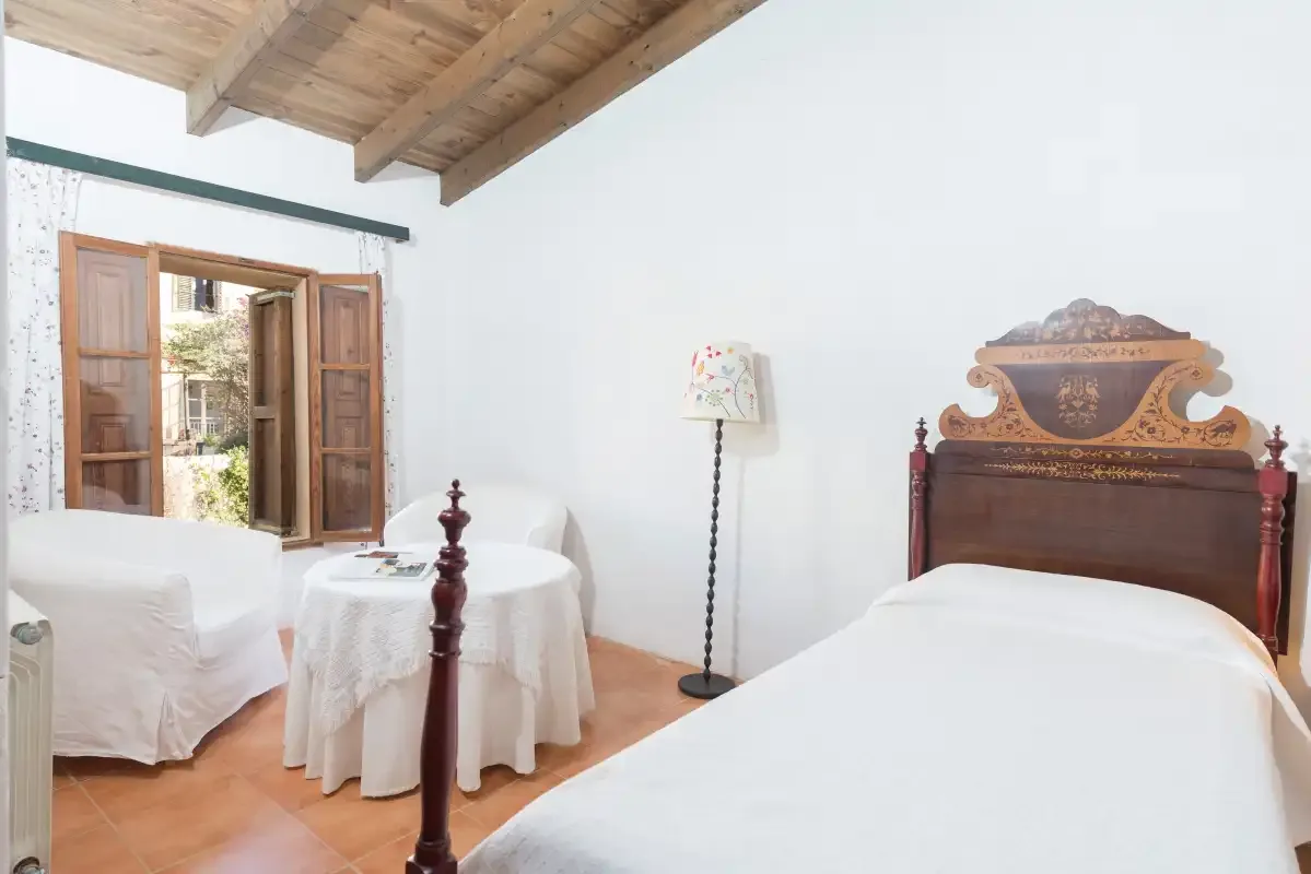 Un dormitorio con dos camas, una pequeña mesa redonda y una ventana abierta.