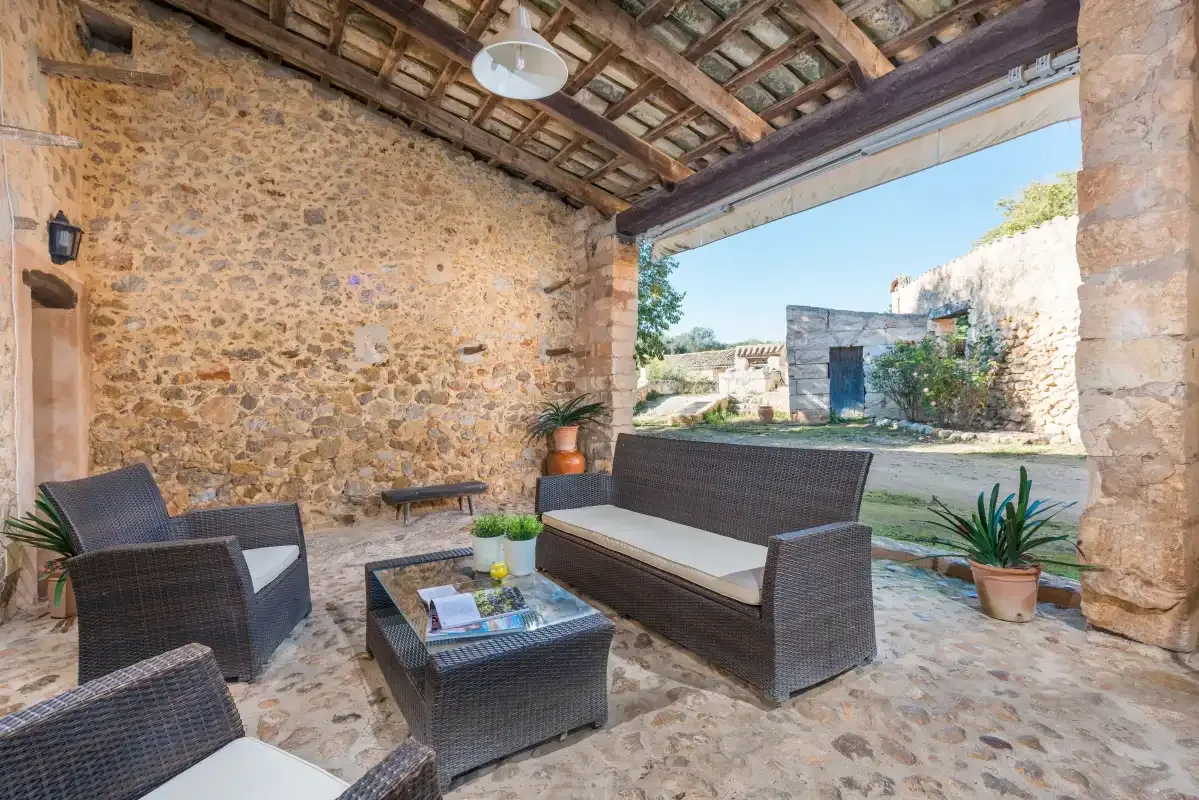 Una zona de estar exterior cubierta con muebles de mimbre y plantas en macetas.