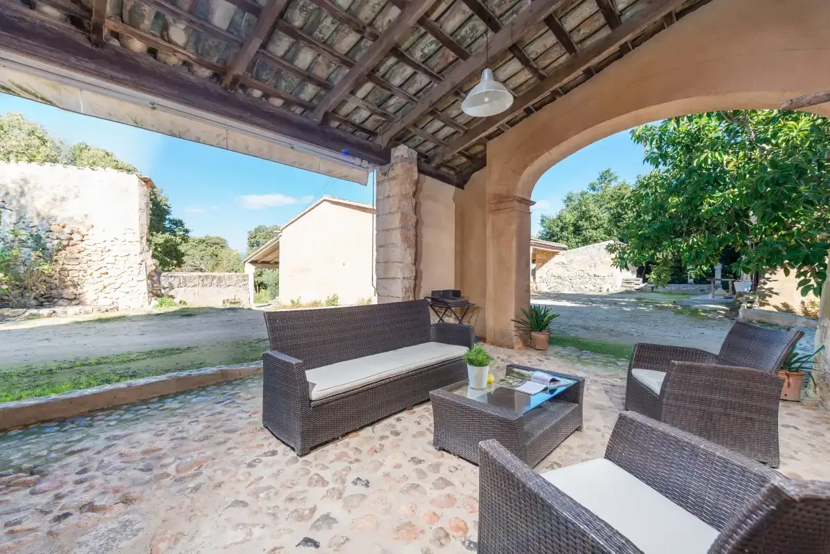 Una zona de estar exterior cubierta se abre a un patio con árboles.