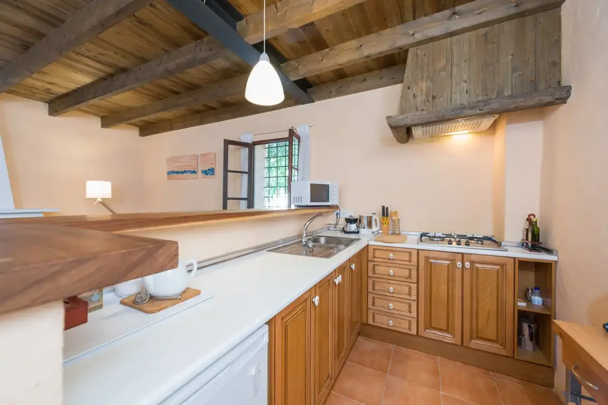Una cocina con armarios de madera y vigas de techo a la vista.