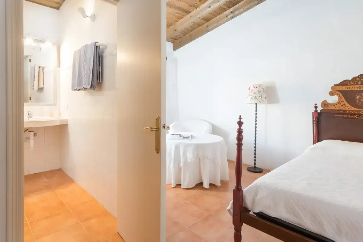 Un dormitorio con un baño contiguo visible a través de una puerta abierta.