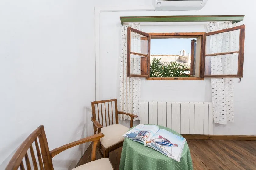Una habitación luminosa con asientos de madera junto a una ventana abierta y un radiador.