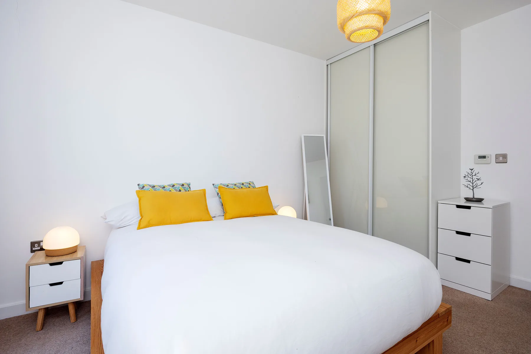 A bright bedroom with a neatly made bed and sliding closet doors.