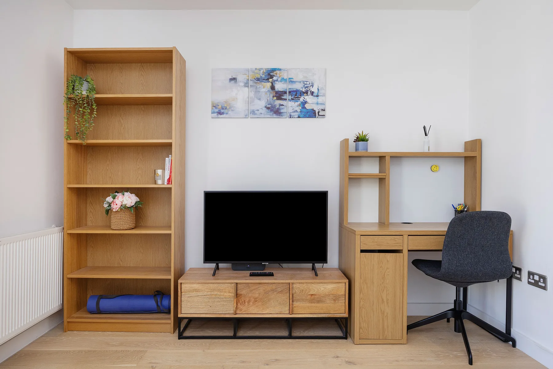 A bright room with wooden shelving, a television, and a desk with seating.