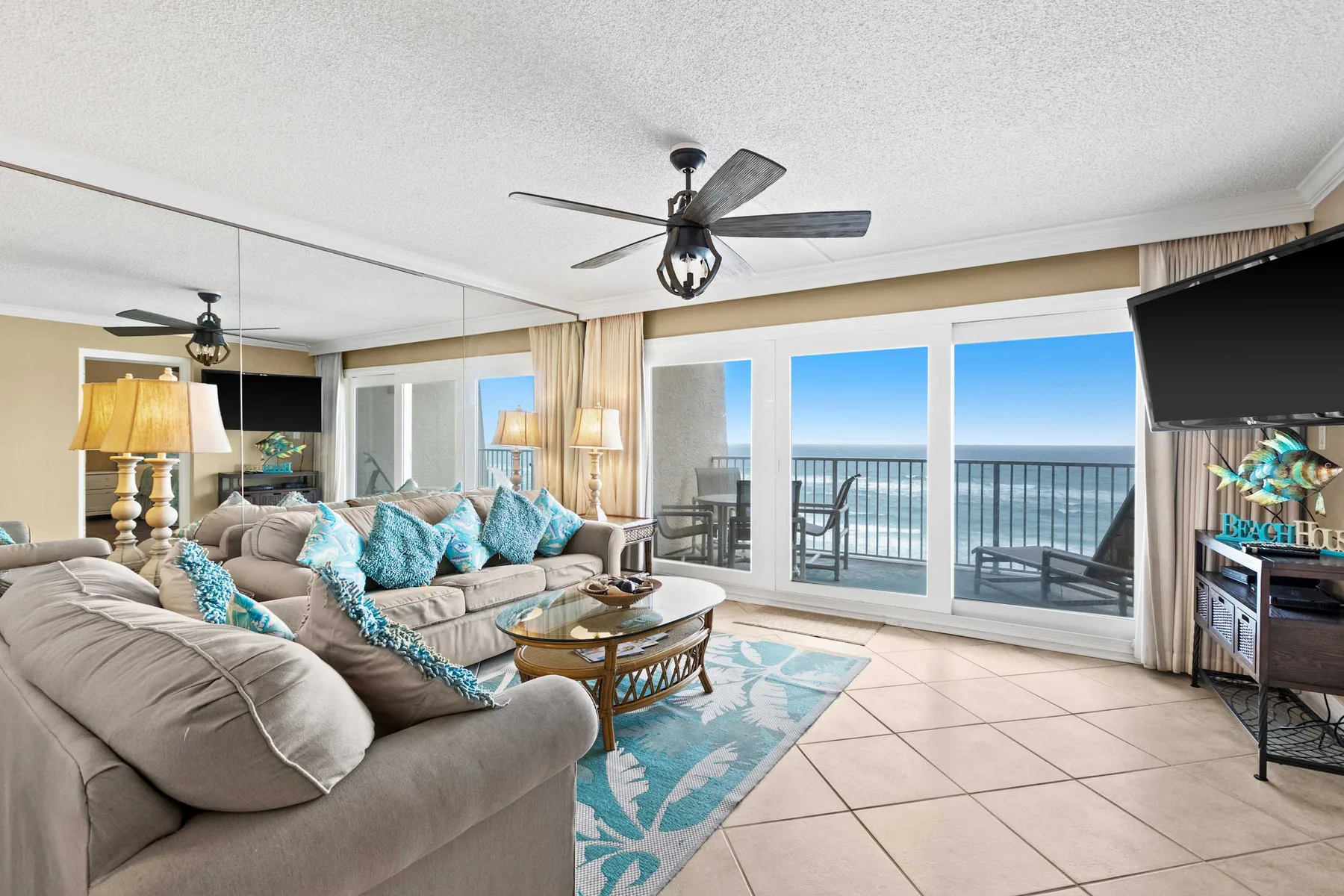 A living room with seating arranged beside large windows overlooking the ocean.