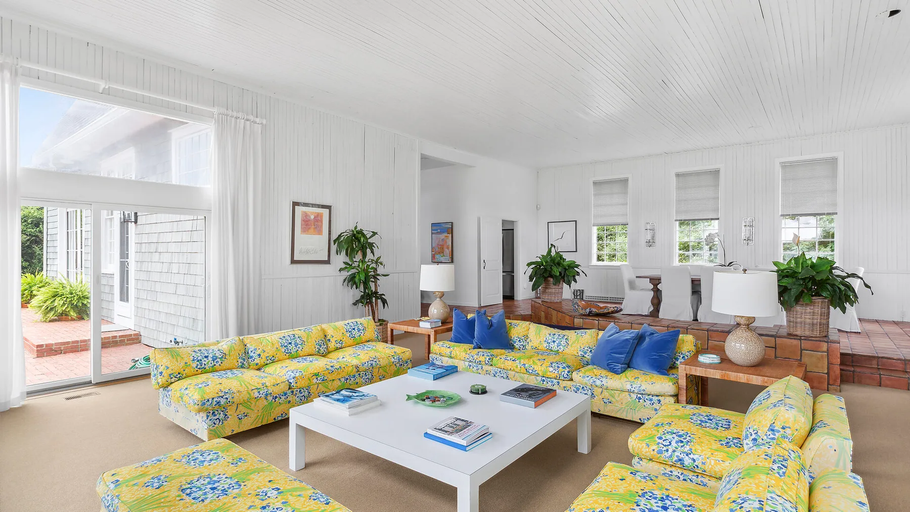 Una sala luminosa con asientos florales de colores alrededor de una mesa de centro blanca.