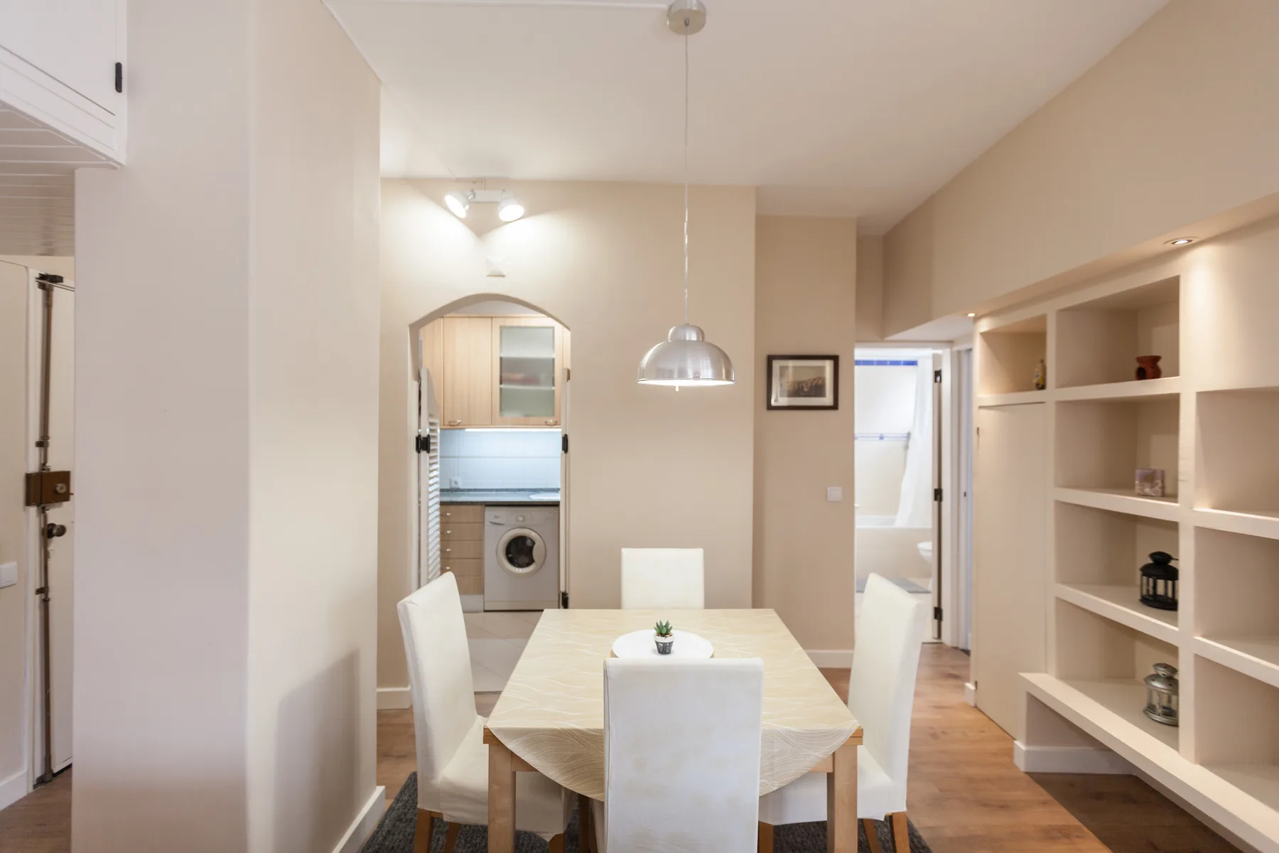 A dining area with a table and chairs beside open shelving.