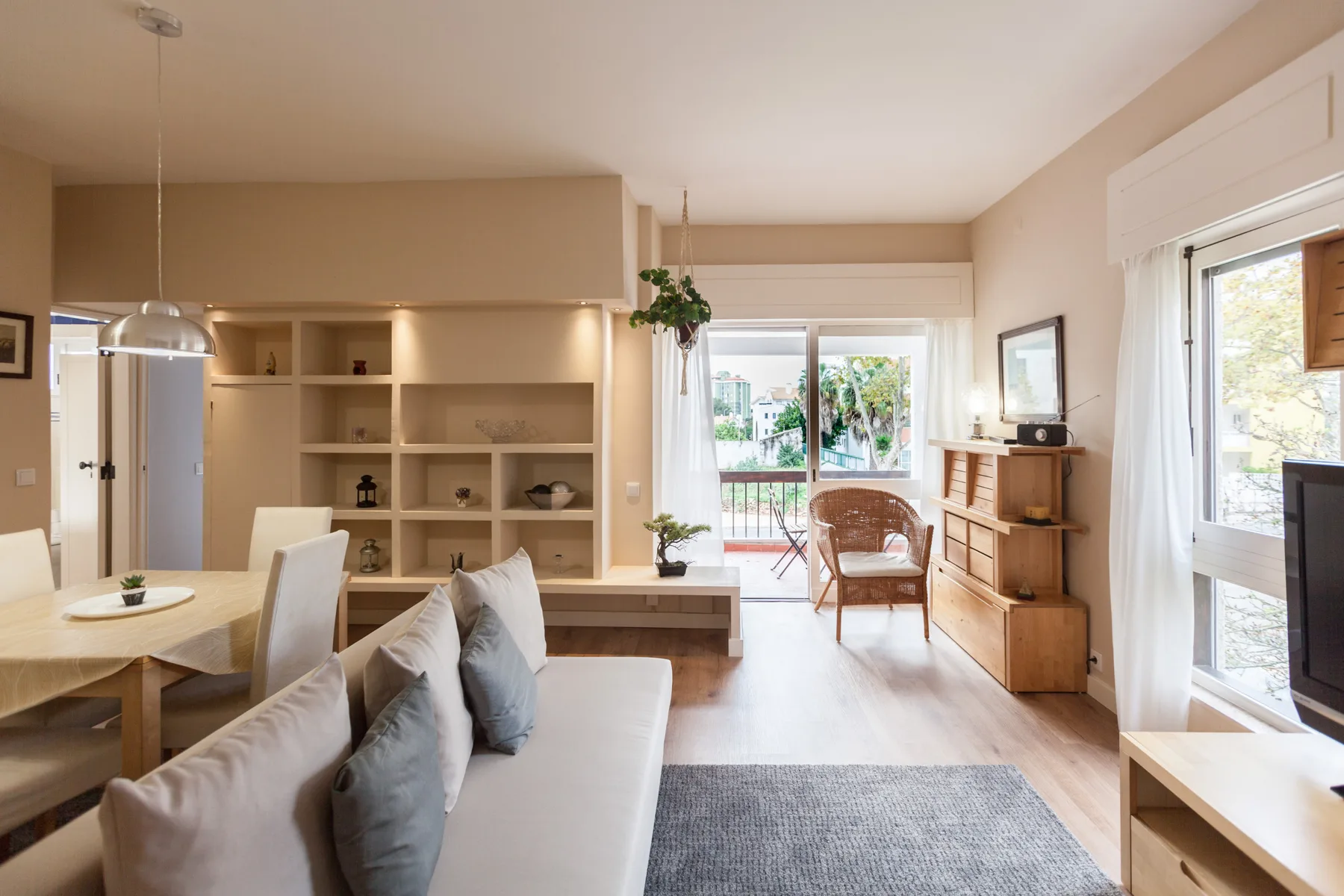 A bright living room with a sofa, dining table, and large windows.
