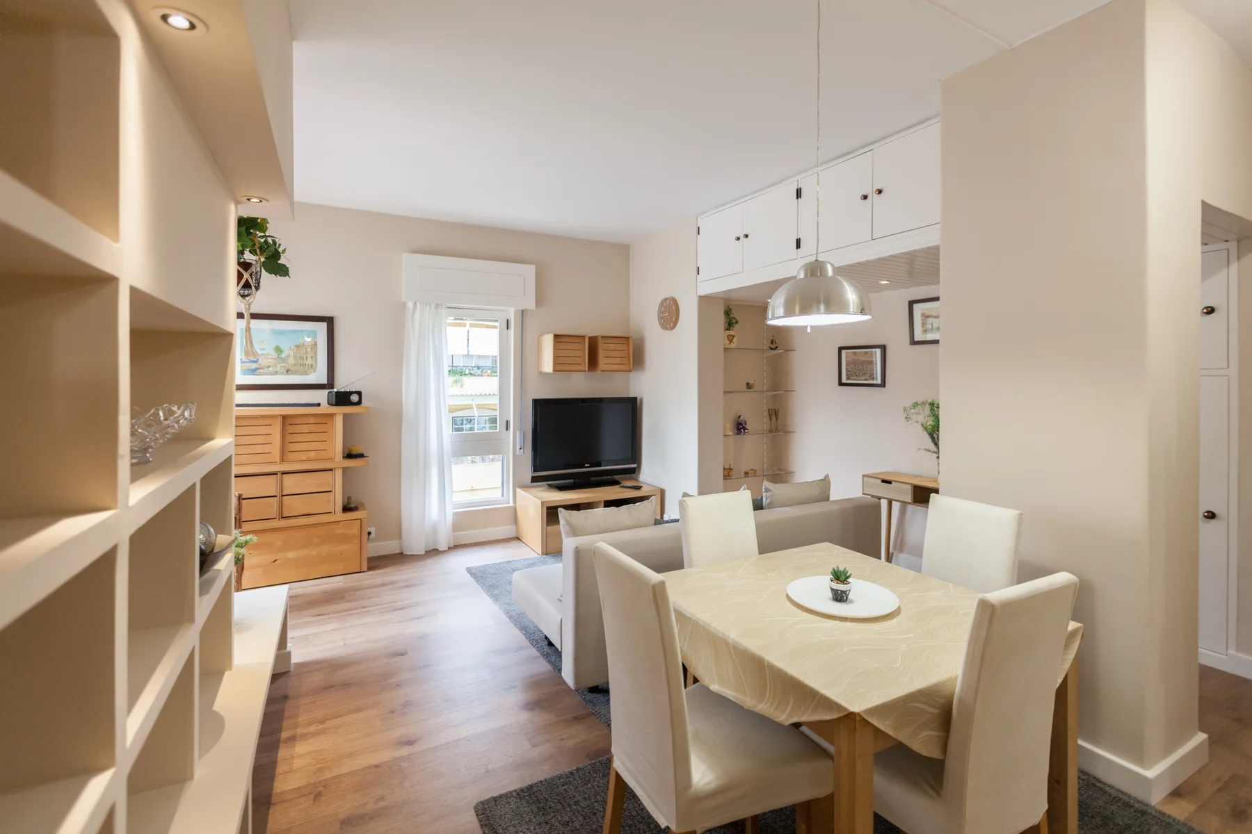A bright living and dining area with a table, seating, and a television.